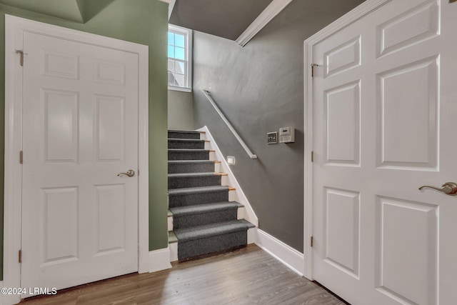 stairs with ornamental molding and hardwood / wood-style floors