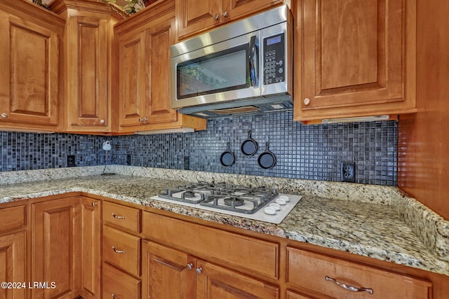 kitchen featuring gas cooktop, light stone counters, and decorative backsplash