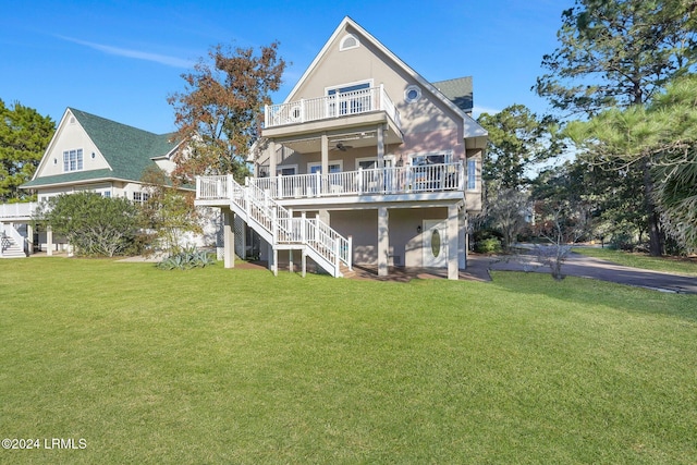 rear view of property with ceiling fan, a balcony, and a lawn