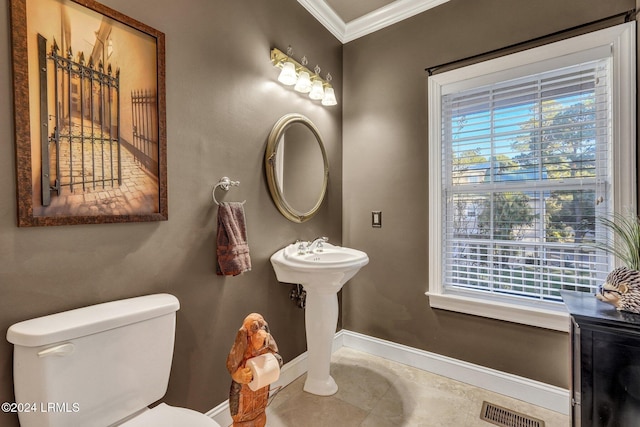 bathroom with tile patterned flooring, crown molding, a wealth of natural light, and toilet