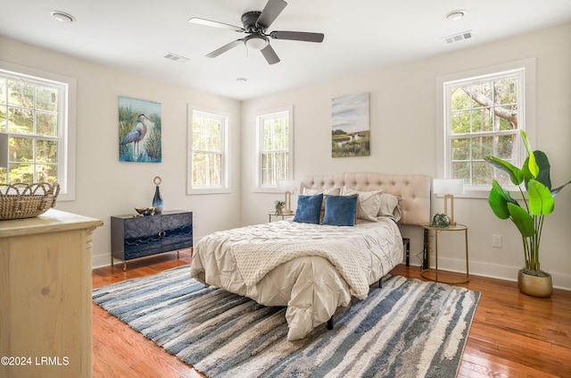 bedroom featuring a ceiling fan, wood finished floors, visible vents, and baseboards