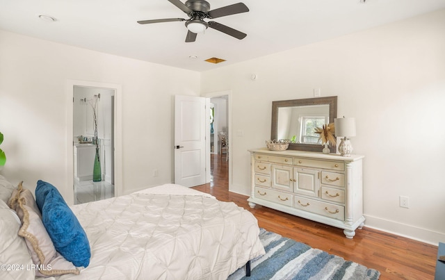 bedroom featuring ensuite bathroom, wood finished floors, a ceiling fan, and baseboards