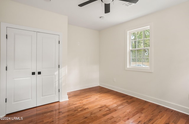 unfurnished bedroom featuring wood finished floors, visible vents, a ceiling fan, baseboards, and a closet