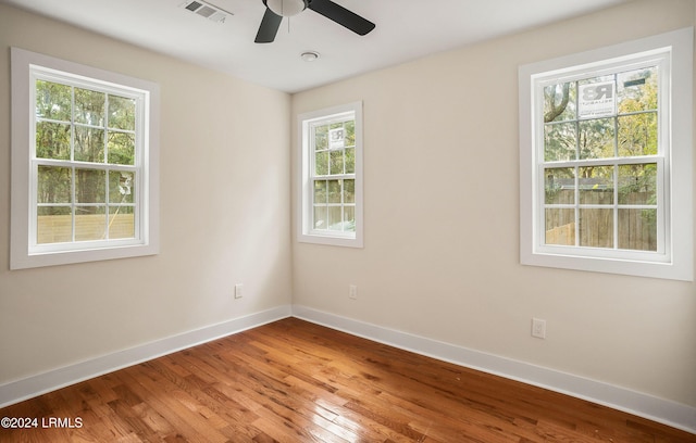 spare room with baseboards, visible vents, ceiling fan, and wood finished floors