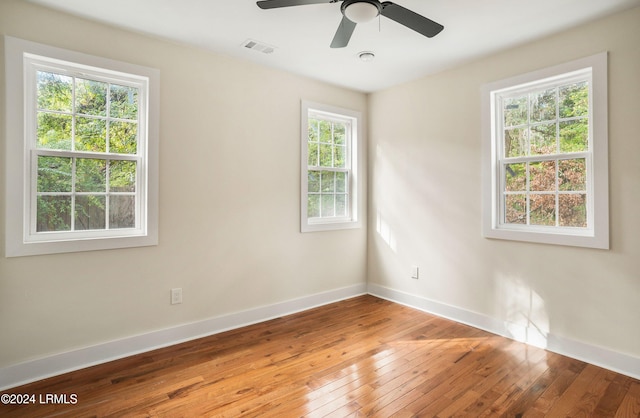 empty room with a ceiling fan, visible vents, baseboards, and wood finished floors