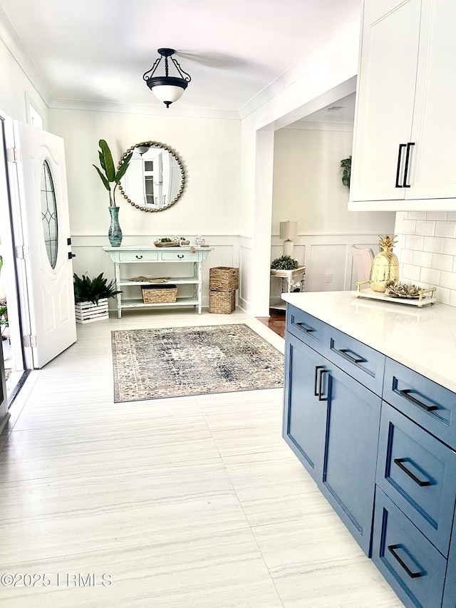 mudroom featuring a wainscoted wall, crown molding, and a decorative wall