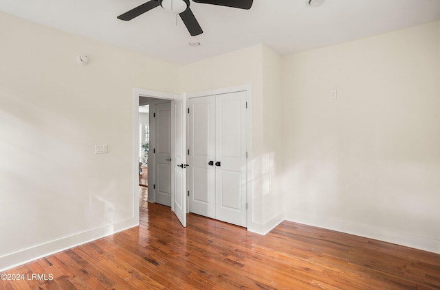 unfurnished bedroom with ceiling fan, a closet, baseboards, and wood finished floors