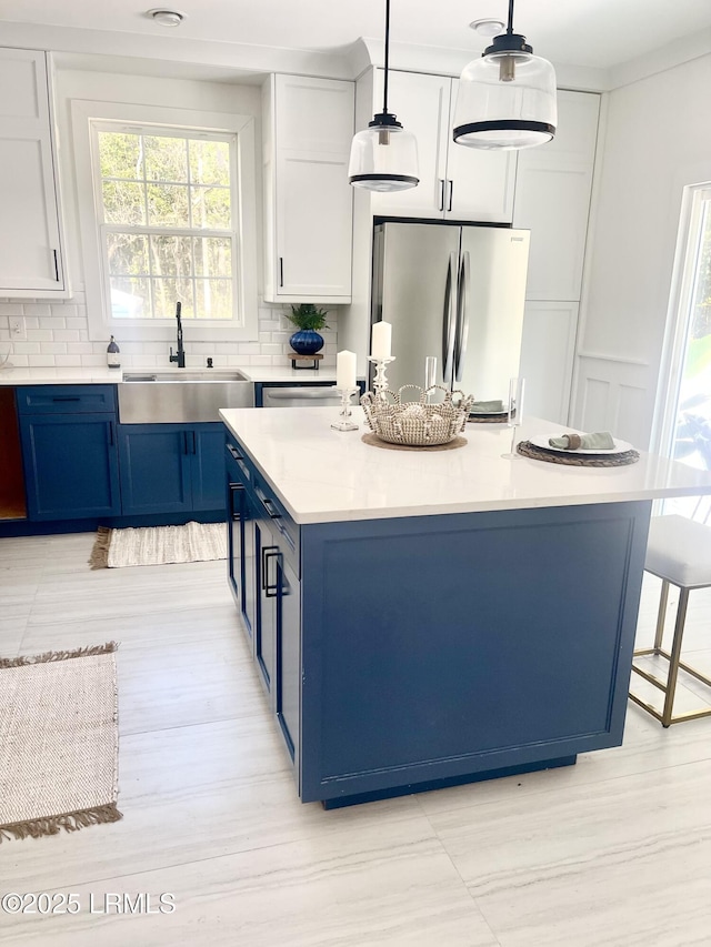 kitchen with blue cabinets, white cabinets, light countertops, freestanding refrigerator, and pendant lighting