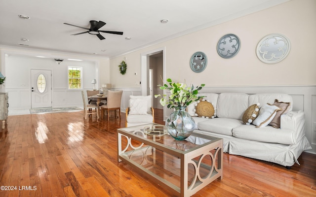 living room with a wainscoted wall, crown molding, a decorative wall, and wood finished floors