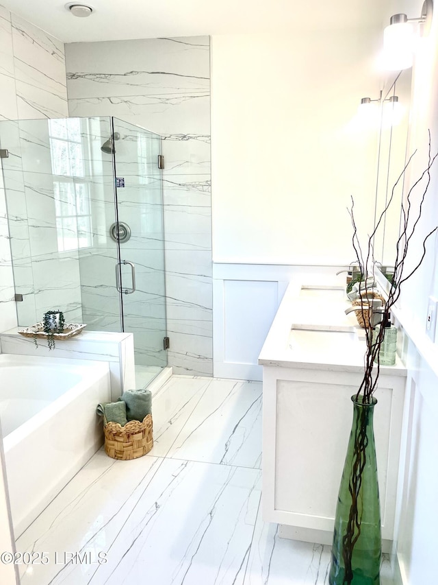 bathroom featuring double vanity, a stall shower, wainscoting, marble finish floor, and a garden tub