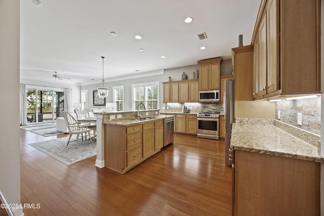 kitchen with sink, hardwood / wood-style flooring, hanging light fixtures, backsplash, and stainless steel appliances