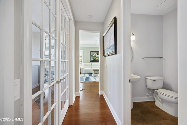 bathroom with french doors, toilet, and hardwood / wood-style floors