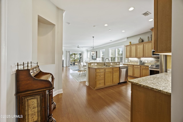kitchen featuring sink, appliances with stainless steel finishes, hardwood / wood-style floors, decorative light fixtures, and kitchen peninsula