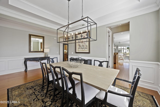 dining space with a raised ceiling, crown molding, and dark hardwood / wood-style flooring