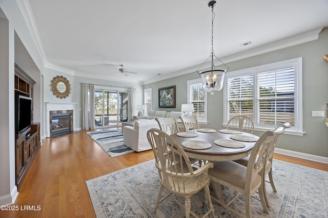 dining space featuring ceiling fan with notable chandelier, light hardwood / wood-style flooring, and ornamental molding