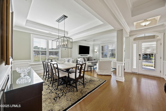 dining room with hardwood / wood-style flooring, plenty of natural light, crown molding, and a raised ceiling