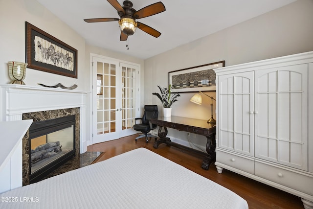 bedroom featuring dark hardwood / wood-style flooring, a fireplace, french doors, and ceiling fan