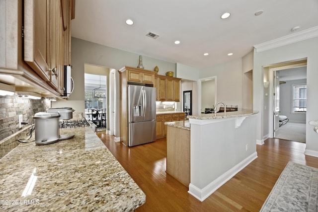 kitchen with light hardwood / wood-style flooring, a breakfast bar area, light stone counters, and stainless steel fridge with ice dispenser