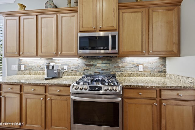 kitchen with tasteful backsplash, appliances with stainless steel finishes, and light stone counters