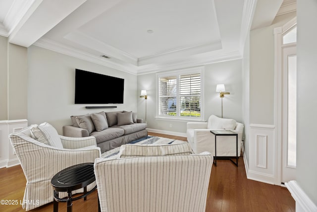 living room with a tray ceiling, dark wood-type flooring, and ornamental molding