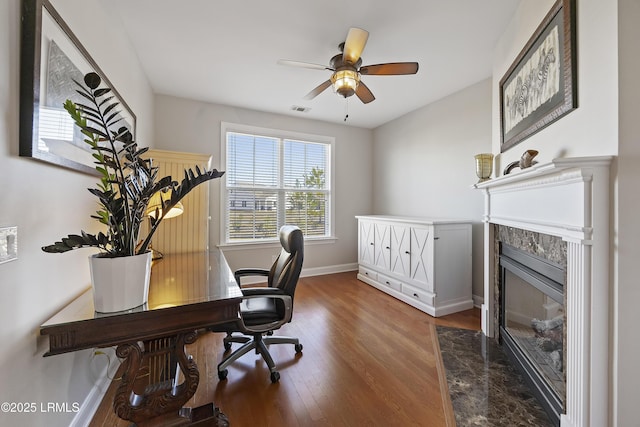 office area featuring ceiling fan, a fireplace, and dark hardwood / wood-style floors