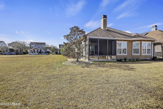 back of property with a yard and a sunroom