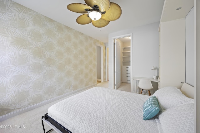 bedroom with light carpet, a spacious closet, a closet, and ceiling fan