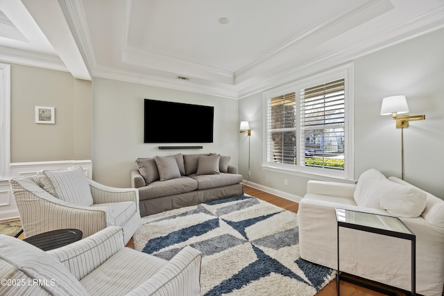 living room with ornamental molding, a raised ceiling, and hardwood / wood-style floors