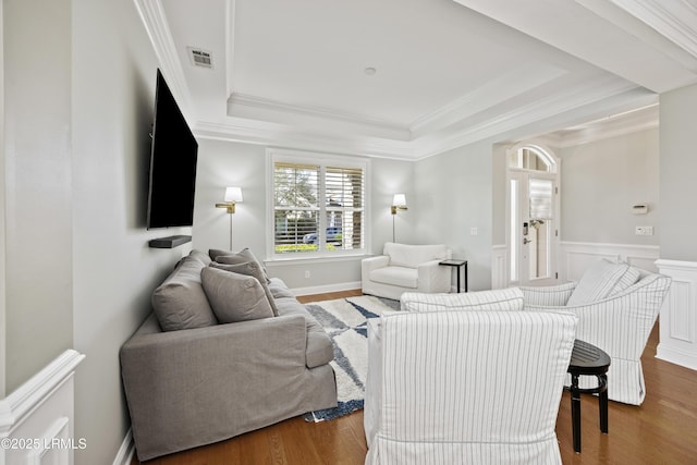 living room featuring hardwood / wood-style flooring, crown molding, and a tray ceiling