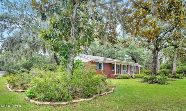 ranch-style home featuring a front yard, covered porch, and brick siding