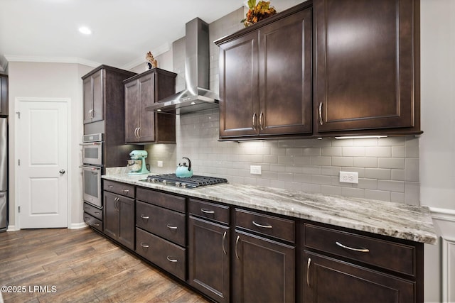 21 Heathrow Ave, Bluffton, SC 29910 - kitchen featuring wall chimney range hood, stainless steel appliances, dark wood-style flooring, light stone counters, and crown molding