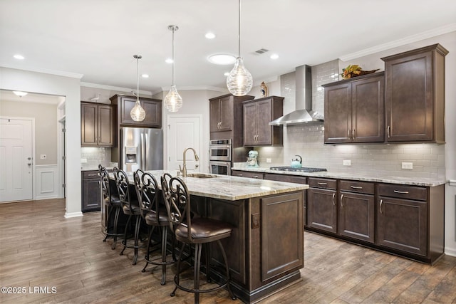 21 Heathrow Ave, Bluffton, SC 29910 - kitchen featuring wall chimney range hood, stainless steel appliances, dark wood-style flooring, dark brown cabinets, and a kitchen bar