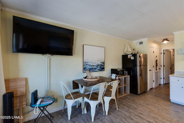 dining area featuring crown molding, visible vents, and wood finished floors