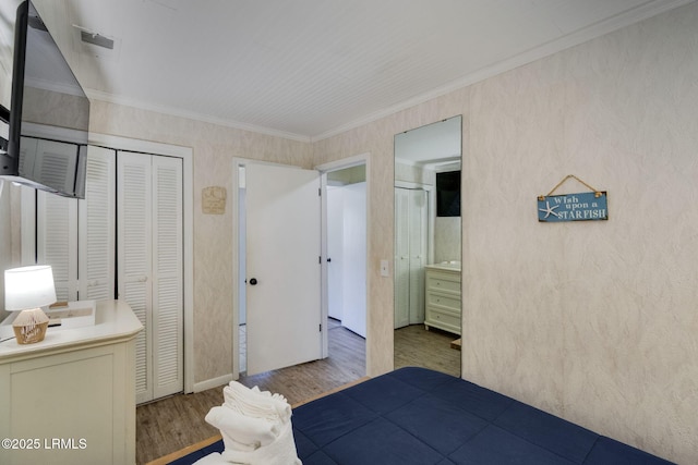 unfurnished bedroom featuring a closet, visible vents, crown molding, and wood finished floors