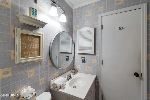 bathroom with toilet, crown molding, tile walls, and vanity