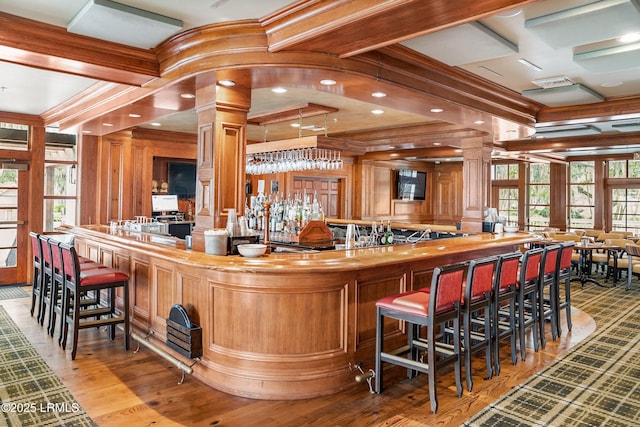 bar featuring decorative columns, crown molding, coffered ceiling, and butcher block countertops