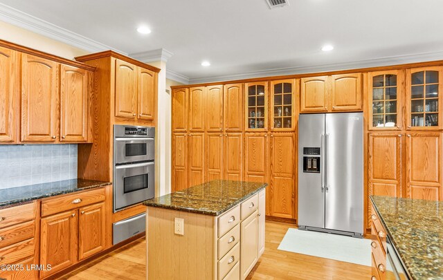 kitchen with stainless steel appliances, light hardwood / wood-style floors, a kitchen island, and dark stone counters