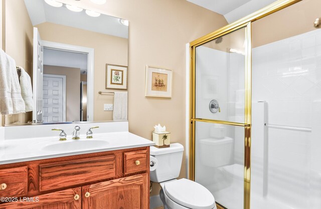 bathroom featuring vanity, toilet, and a shower with shower door