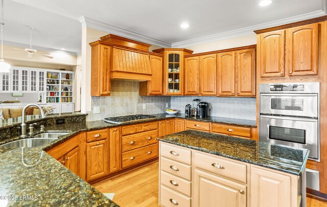 kitchen featuring sink, stainless steel appliances, dark stone counters, and light wood-type flooring