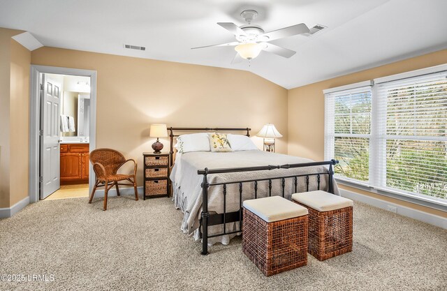 bedroom featuring ensuite bath, vaulted ceiling, light colored carpet, and ceiling fan