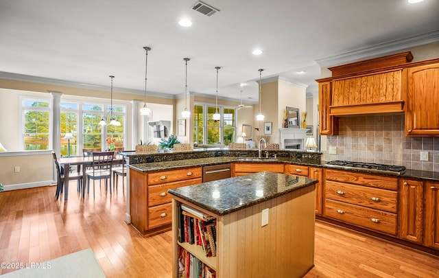 kitchen with sink, light hardwood / wood-style flooring, hanging light fixtures, stainless steel appliances, and a center island