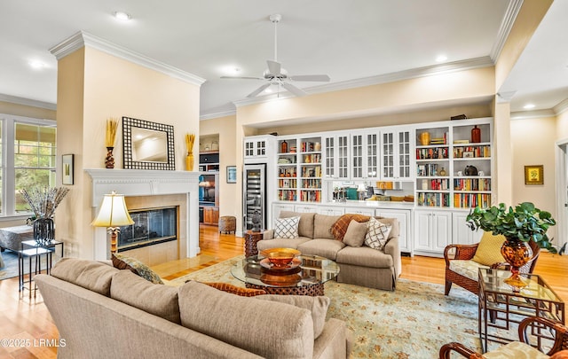 living room featuring a tiled fireplace, ornamental molding, and light hardwood / wood-style floors