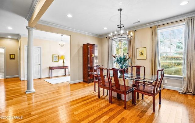 dining space featuring a notable chandelier, crown molding, light wood-type flooring, and ornate columns