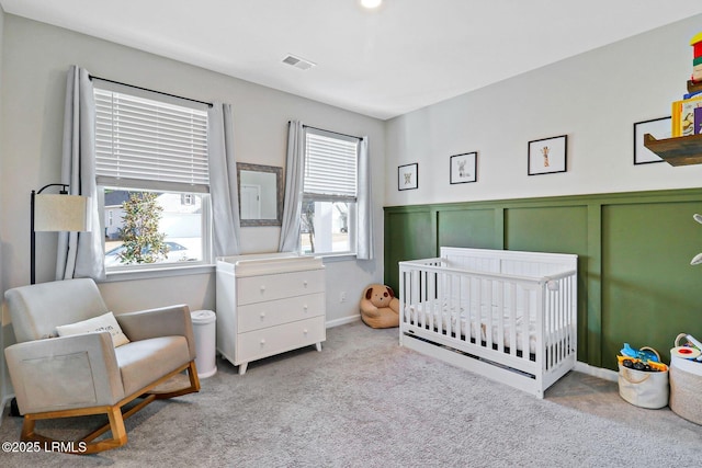 bedroom featuring a nursery area and light carpet