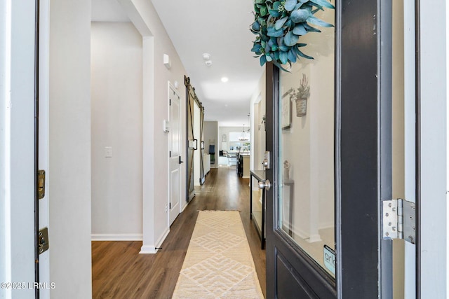 hallway with dark wood-type flooring and a barn door