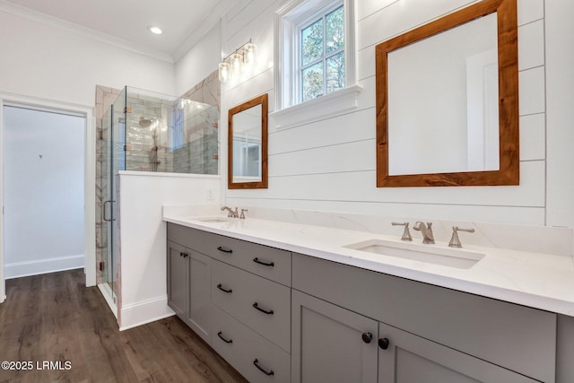 bathroom with ornamental molding, wood-type flooring, a shower with door, and vanity