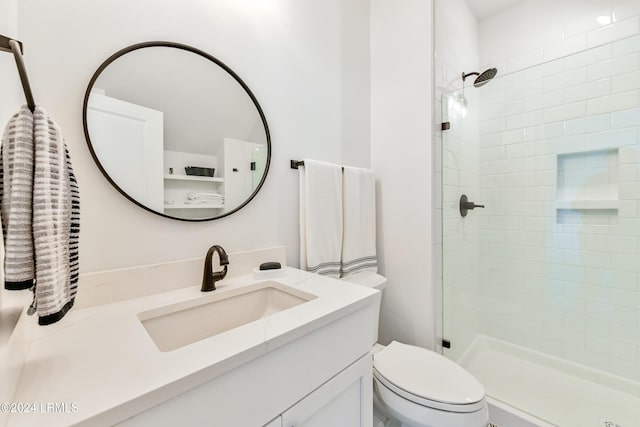 bathroom featuring vanity, a tile shower, and toilet