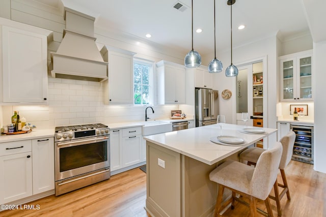 kitchen with appliances with stainless steel finishes, white cabinetry, backsplash, wine cooler, and a kitchen island