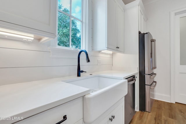 kitchen with white cabinetry, appliances with stainless steel finishes, sink, and light hardwood / wood-style flooring