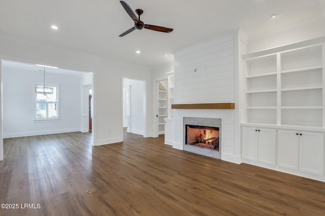 unfurnished living room featuring dark hardwood / wood-style floors, ceiling fan, and built in shelves